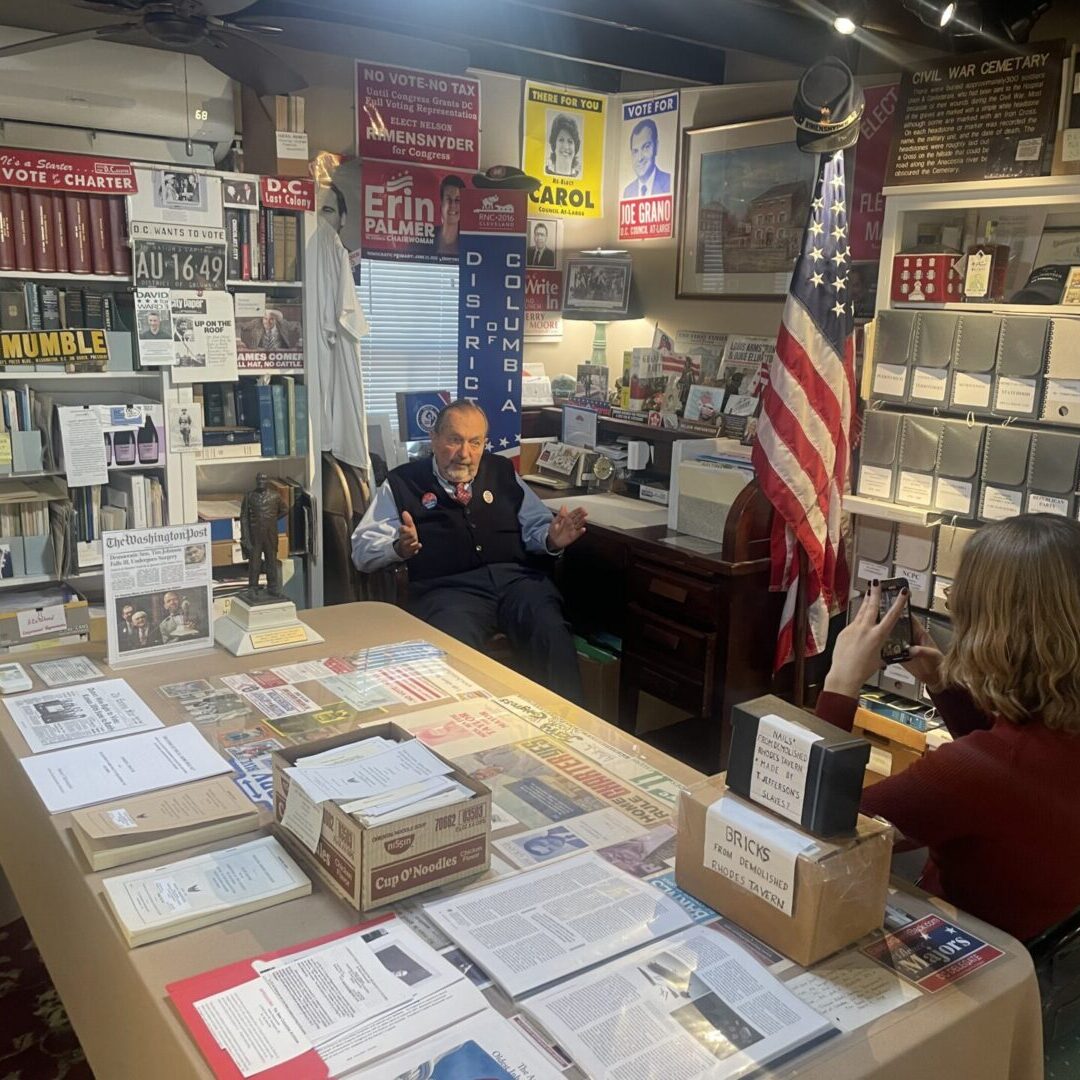 A table with many different mail boxes and people sitting at it.