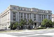 A large white building with trees in front of it.